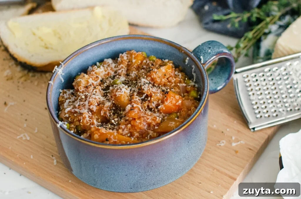 Hearty Quinoa and Vegetable Stew Recipe 11 Quinoa Vegetable Stew served in a blue bowl with sprinkled parmesan cheese on top with crusty bread and a silver grater on the side