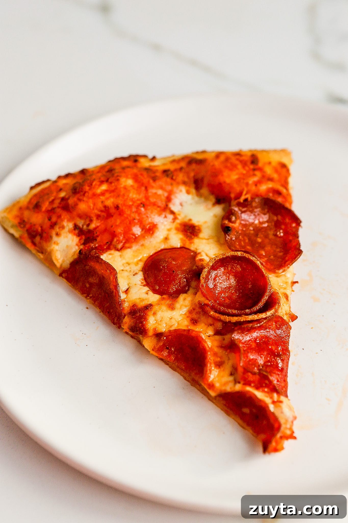 side angle of pepperoni pizza on white plate