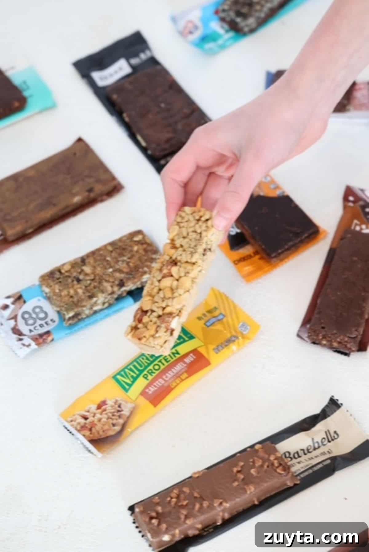 RD-Approved Protein Bars for Adults and Kids 2 A variety of protein bars out of their packages with a child's hand grabbing one.