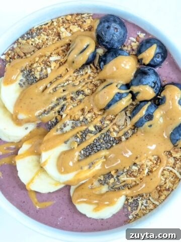 One acai protein bowl topped with toppings served in a white bowl.
