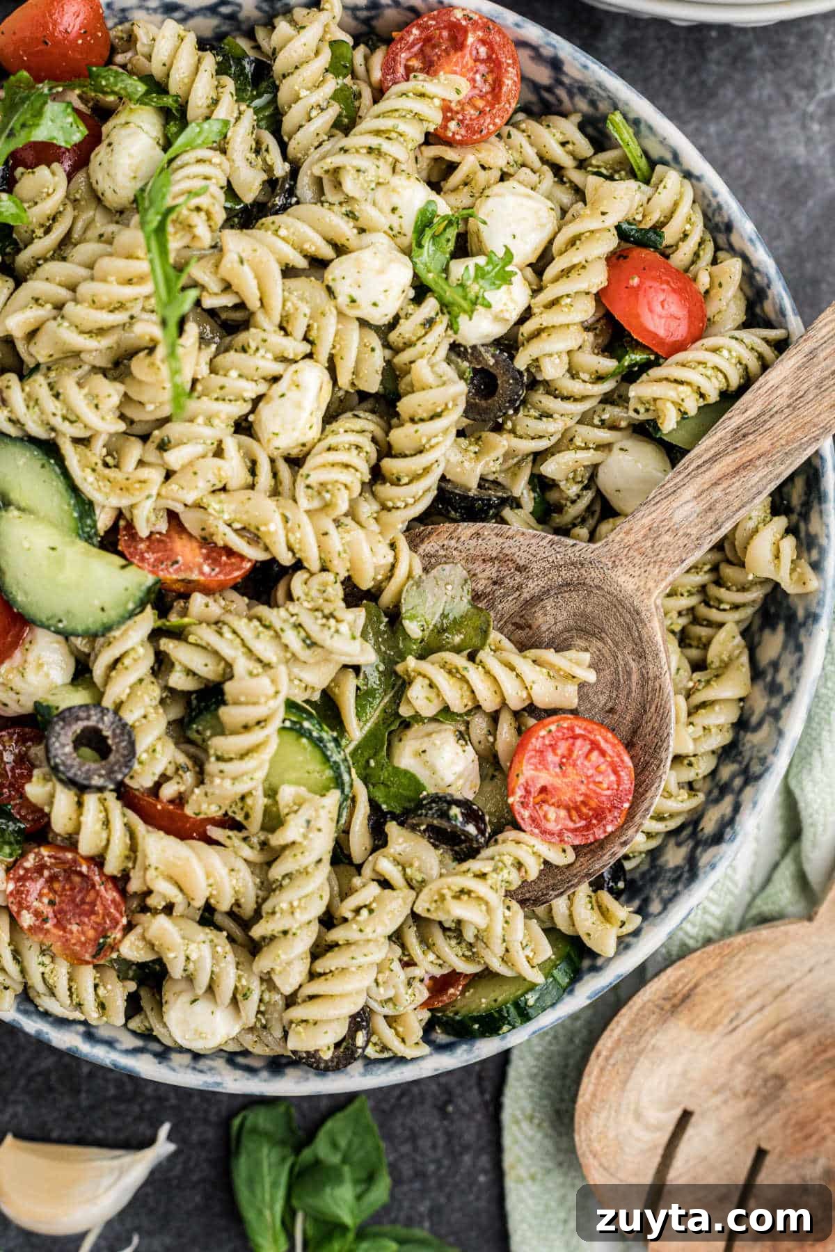 Summer Pesto Pasta Salad with Cherry Tomatoes and Mozzarella 2 Overhead close up shot of a bowl of summer pesto pasta salad with a spoon hanging out in there.