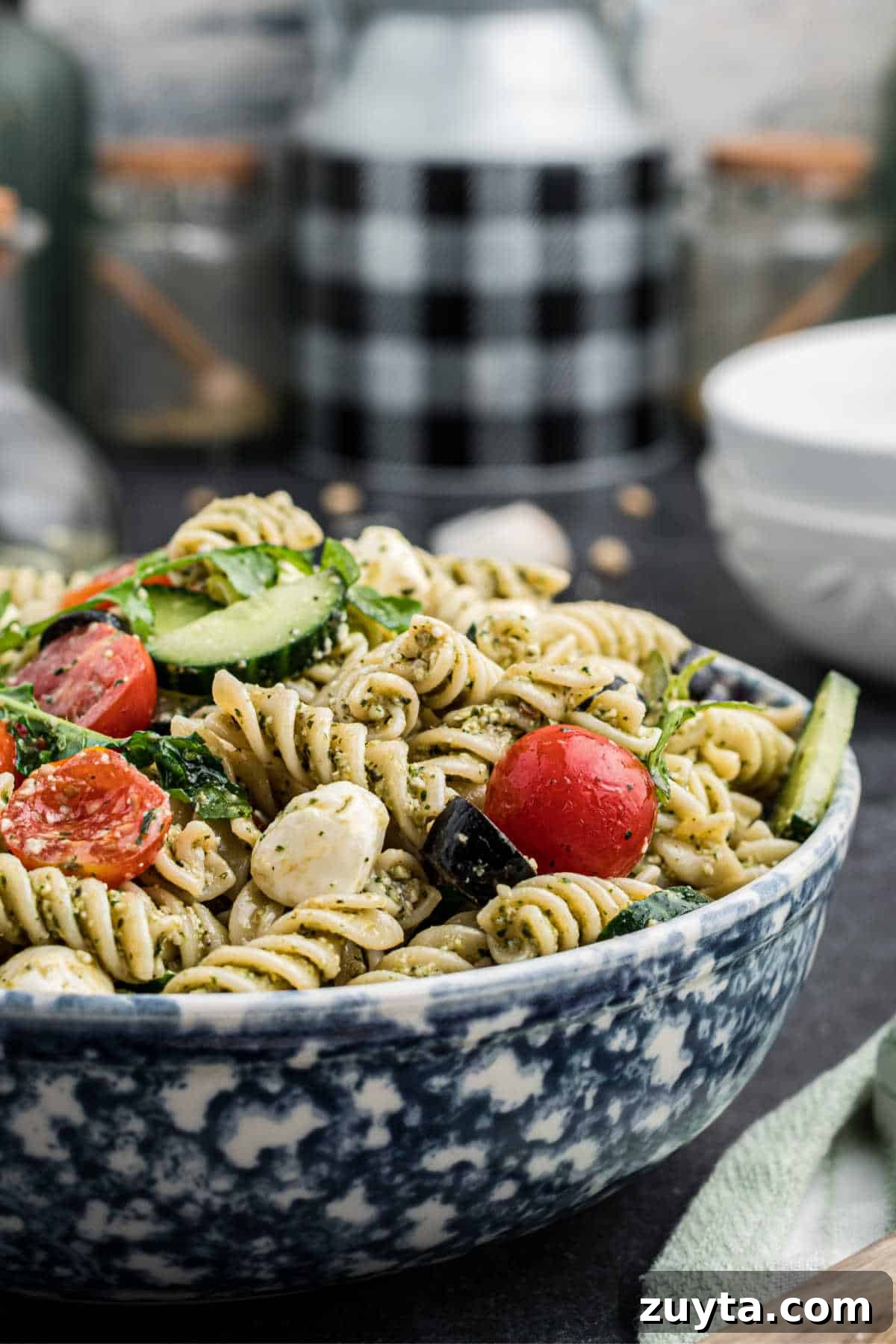 Summer Pesto Pasta Salad with Cherry Tomatoes and Mozzarella 6 Close up side angle shot of a bowl of pesto pasta salad.