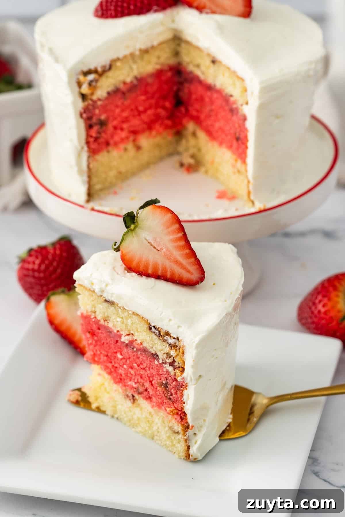 cake with two layers of vanilla one os strawberry with white frosting and a strawberry on top