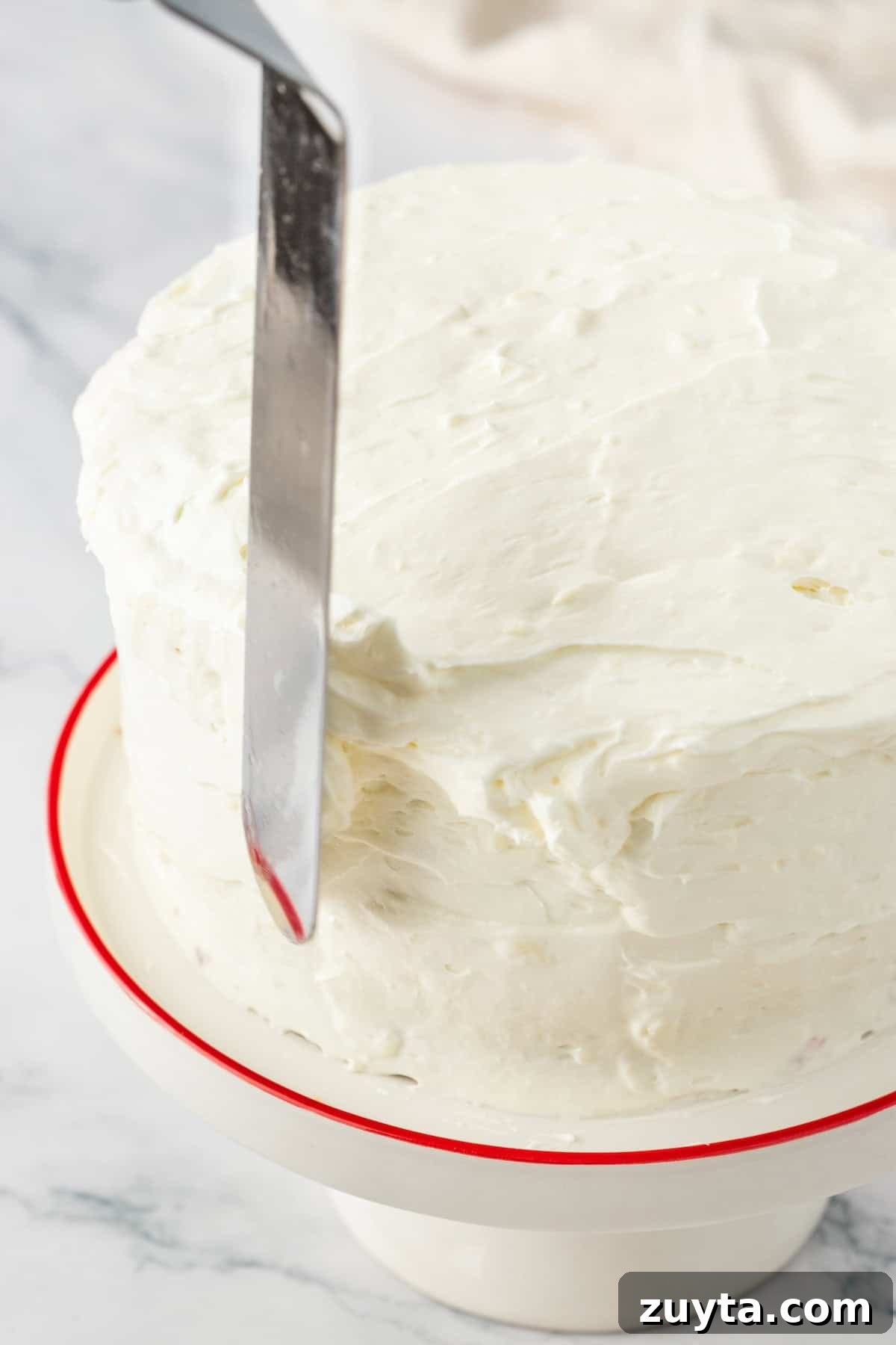 cake being iced with a spatula