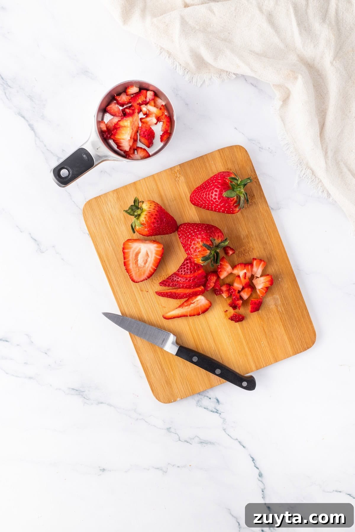 strawberries on a board with some in a measuring cup