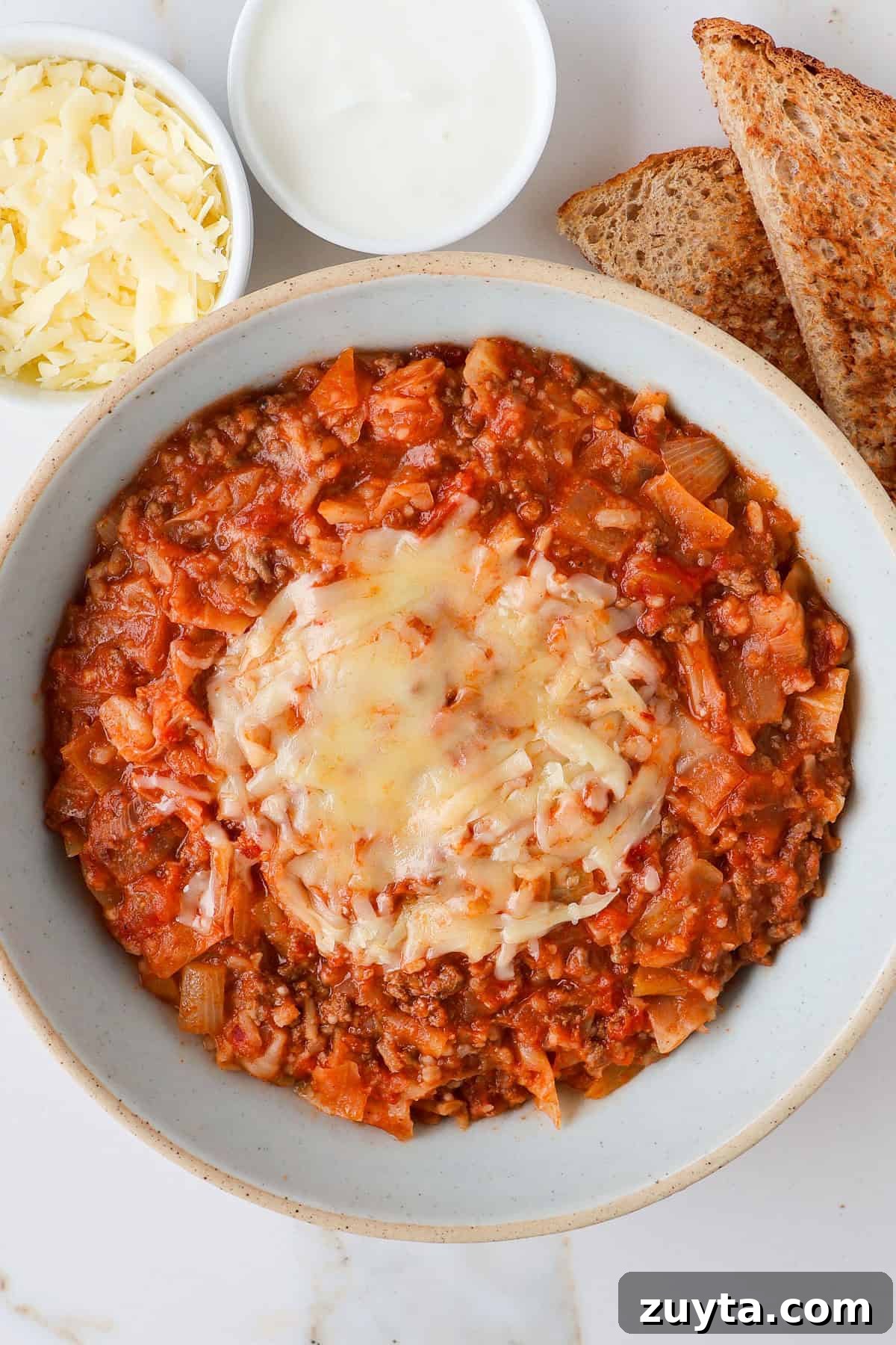 Spicy Chipotle Ground Beef and Cabbage Casserole Recipe 2 Casserole in a bowl with melted cheese and bread on the side.
