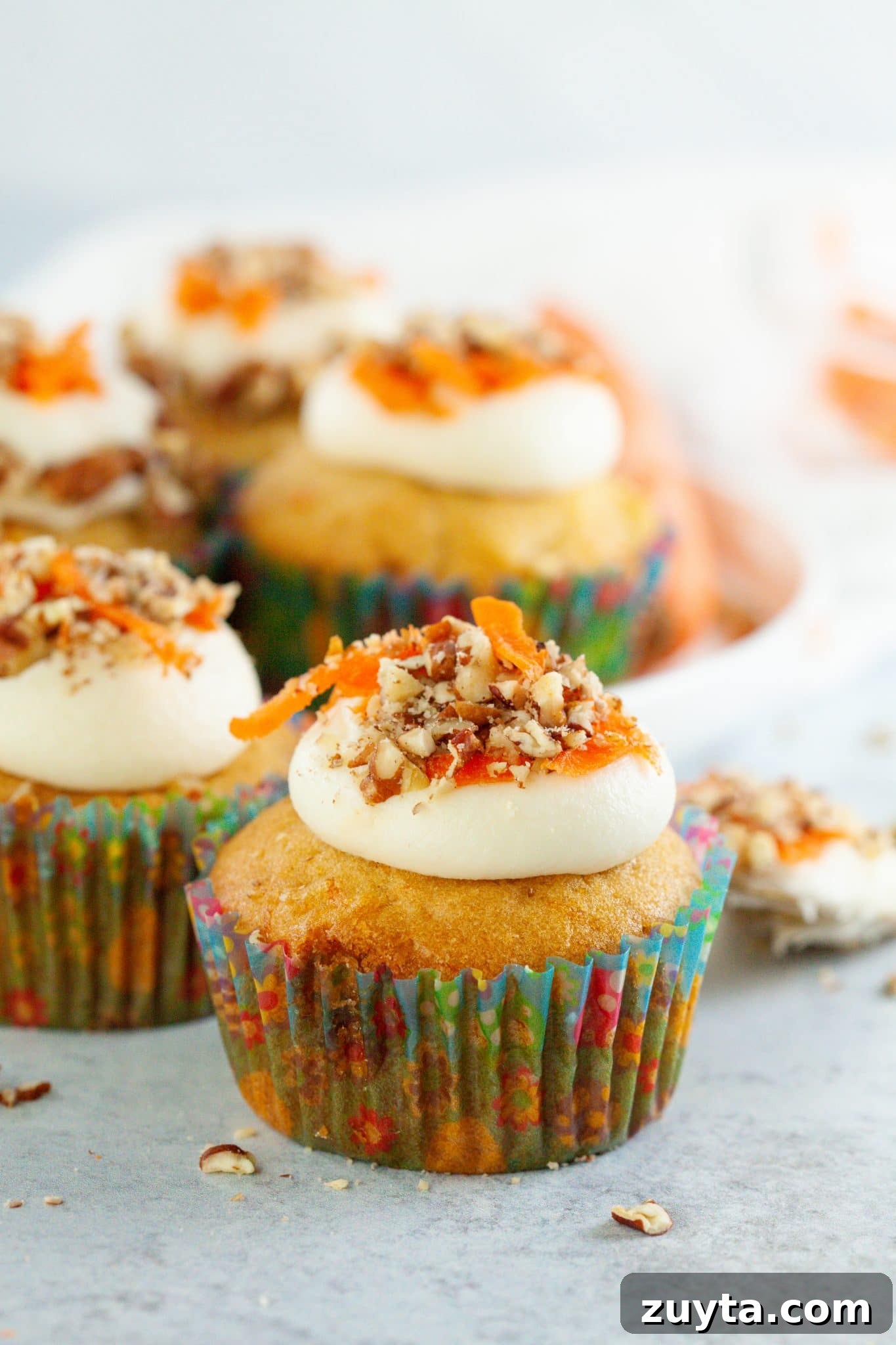 Carrot Cake Cupcakes Recipe with Cream Cheese Frosting 5 Carrot cupcakes beautifully decorated with cream cheese frosting, shredded carrots, and chopped pecans.