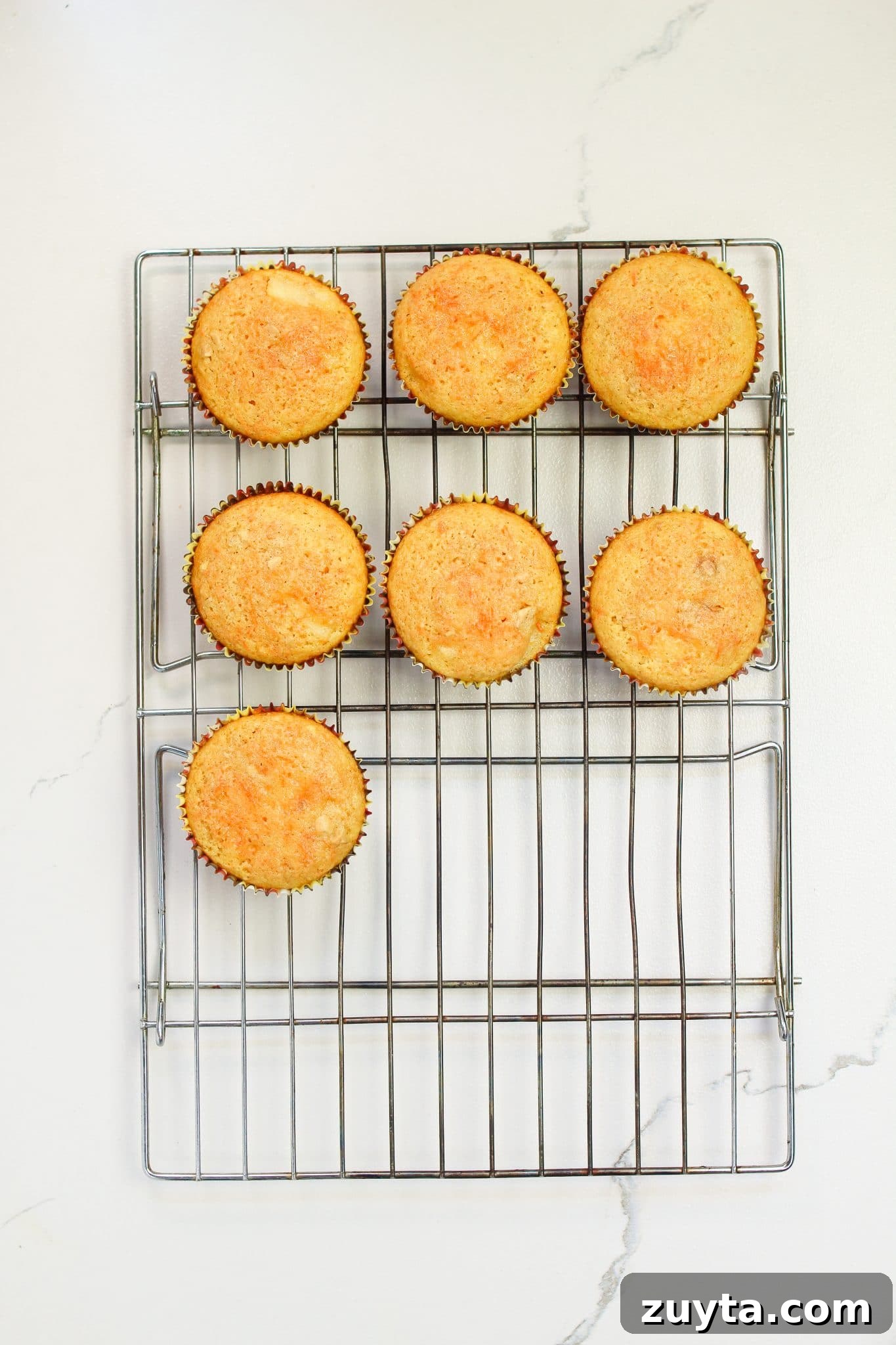 Carrot Cake Cupcakes Recipe with Cream Cheese Frosting 7 cupcakes cooling on a rack.
