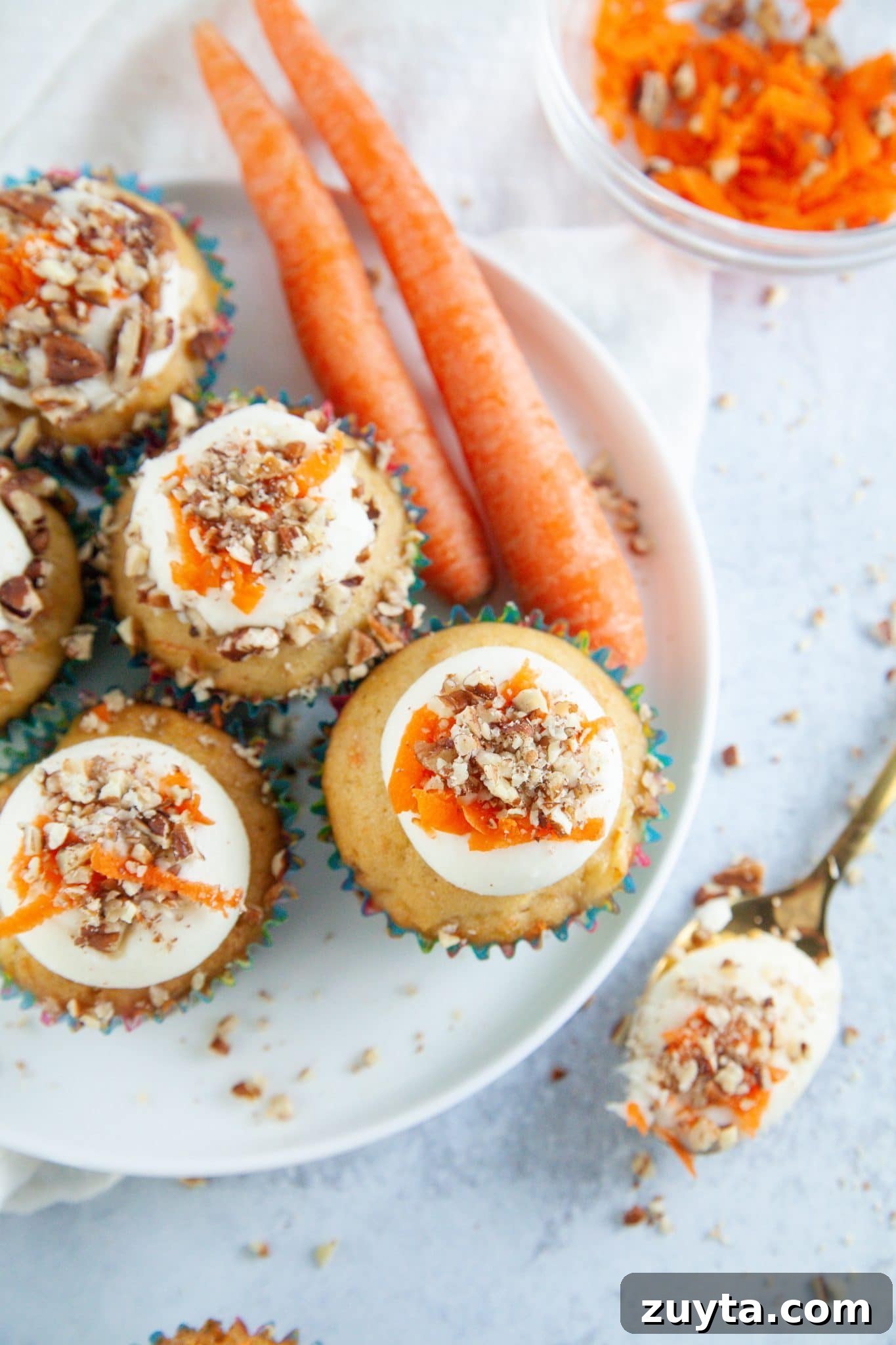 Carrot Cake Cupcakes Recipe with Cream Cheese Frosting 8 cupcakes recipe presented on a platter with frosting and grated carrots.
