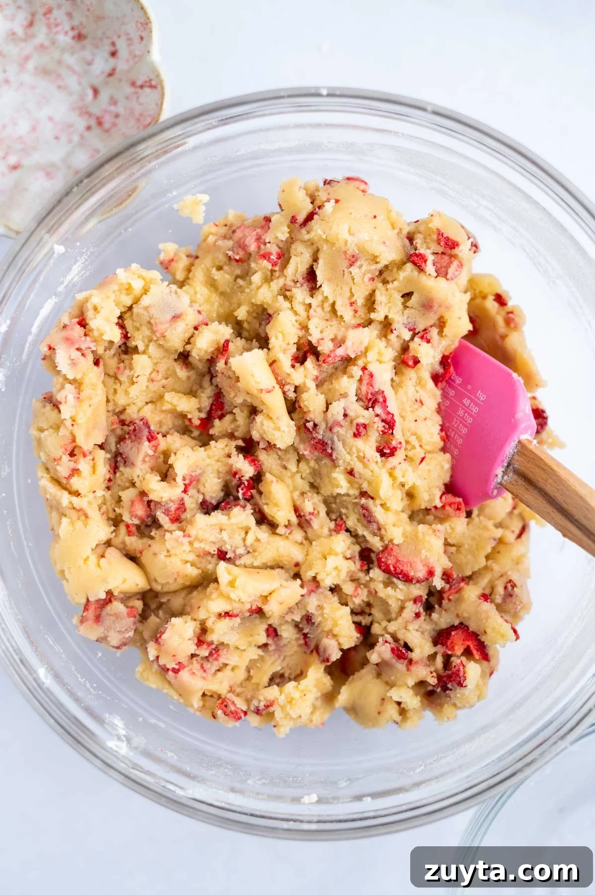 strawberry sugar cookie dough in a mixing bowl with a spatula