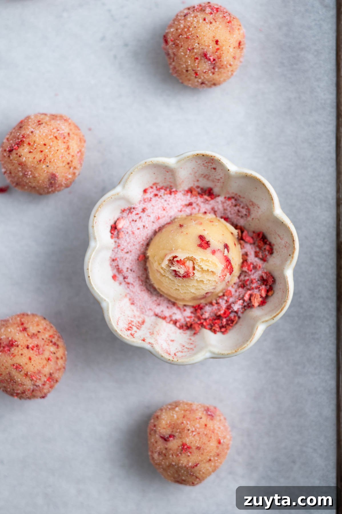 cookie dough ball in a bowl of strawberry sugar