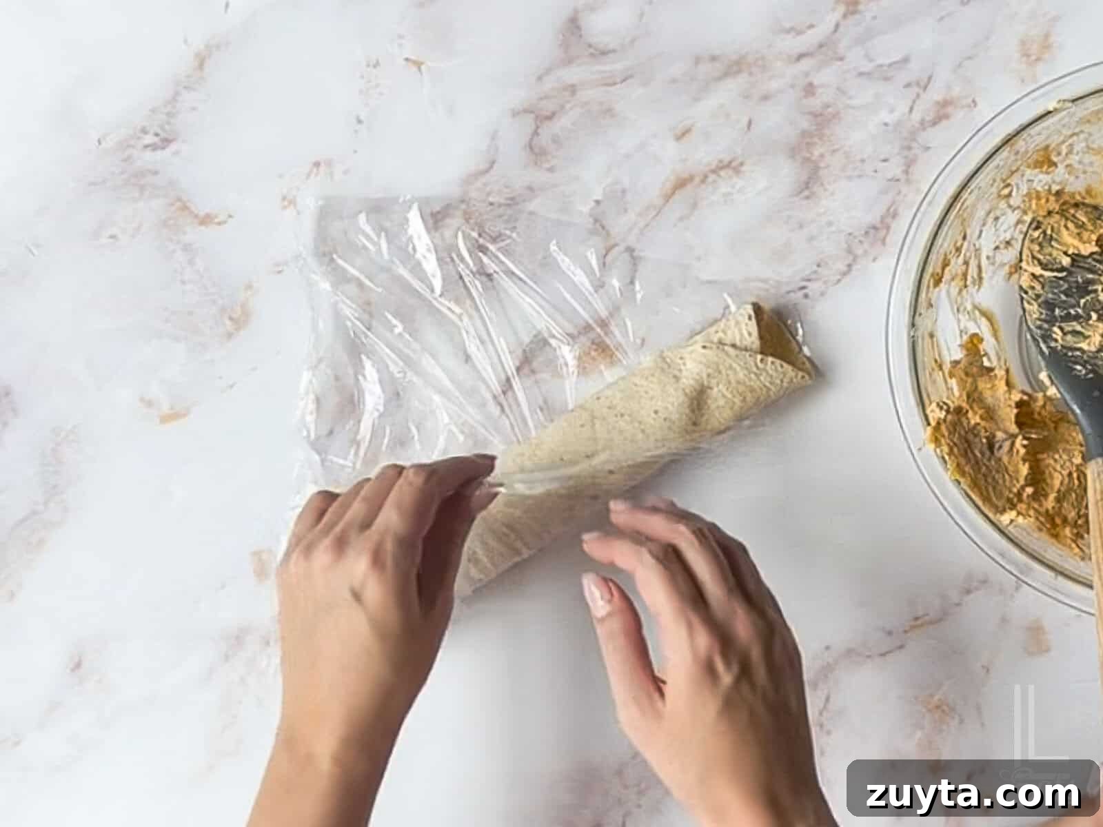 Buffalo Chicken Pinwheels Appetizer Recipe 9 wrapping tortilla roll-up in plastic wrap.