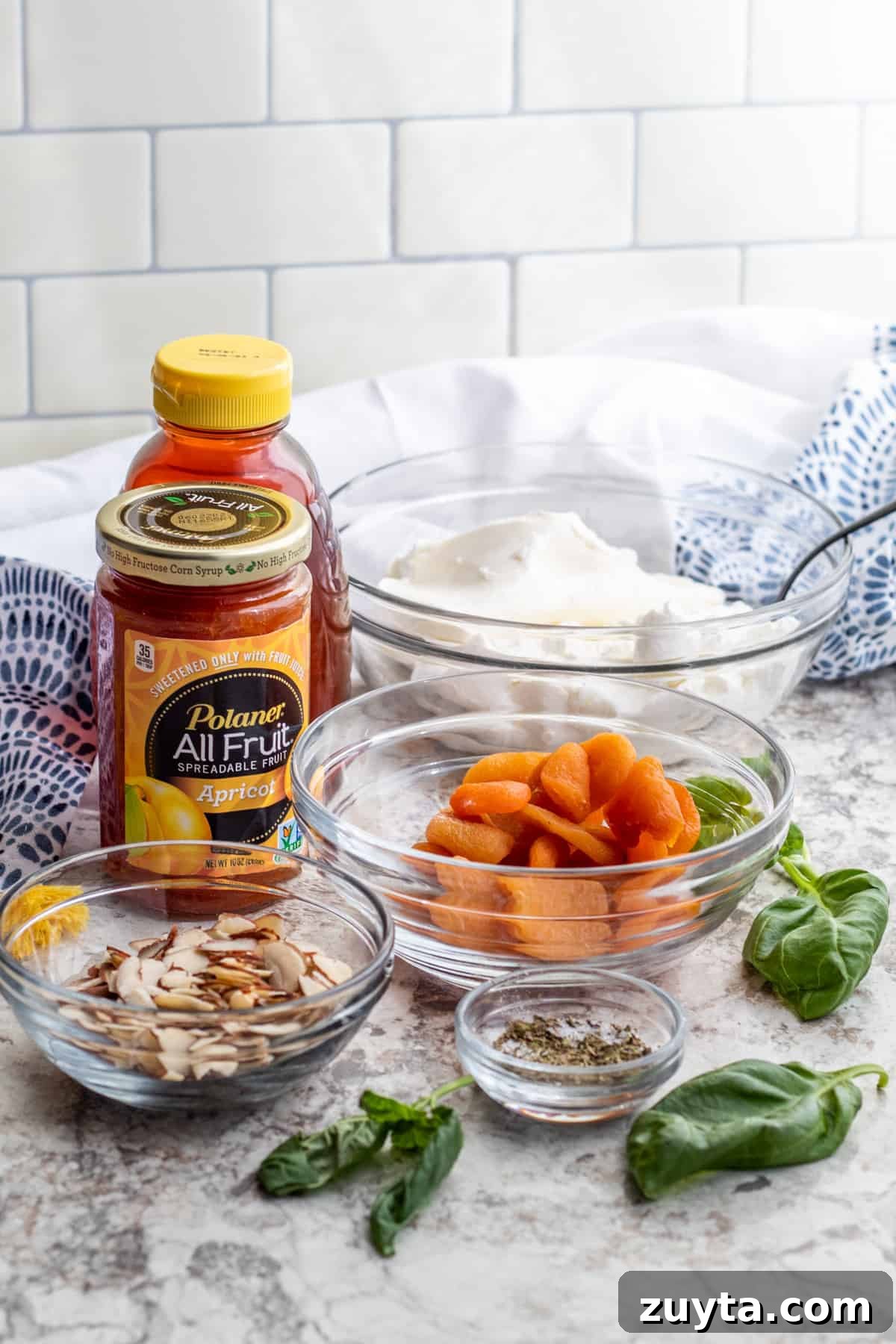 Honey Apricot Goat Cheese Log with Toasted Almonds 3 Recipe ingredients in glass bowls and packaging on white counter top.