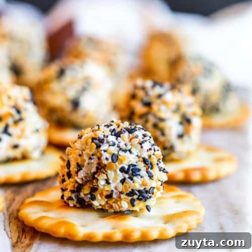 Honey Apricot Goat Cheese Log with Toasted Almonds 10 Cheese Ball Bite on a round cracker on a marble and wood cutting board.