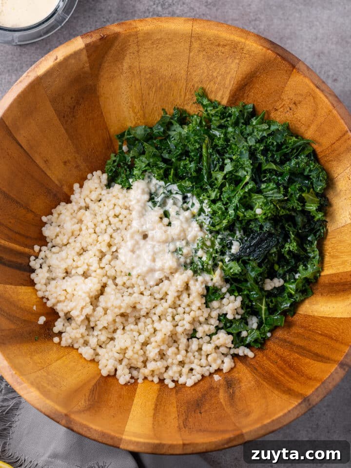kale, couscous and a couple tablespoons of dressing in a large wooden salad bowl