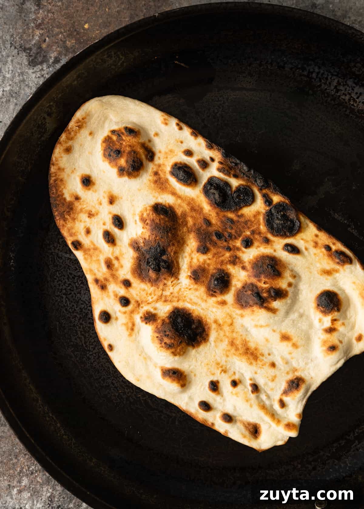 How to Make Naan at Home: Authentic Indian Flatbread 11 charred Indian flatbread in skillet