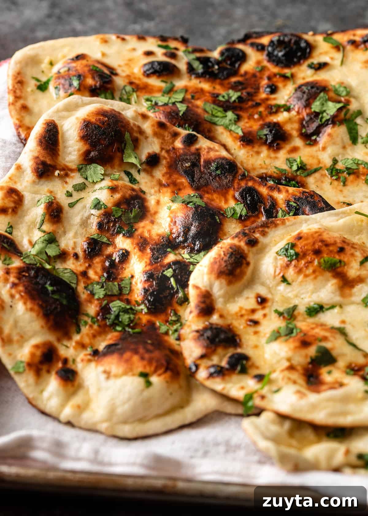 How to Make Naan at Home: Authentic Indian Flatbread 13 closeup: buttered naan bread with cilantro on tray