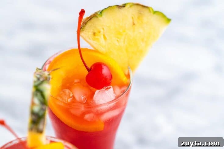 A rum runner cocktail garnished with pineapple and a maraschino cherry.