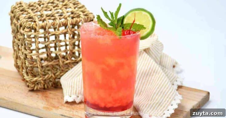 A pink Mai Tai cocktail garnished with mint and lime.