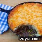 How to make shepherd's pie in a cast iron skillet! Baked recipe has beef filling with peas and corn, topped with mashed potatoes and grated cheddar cheese.