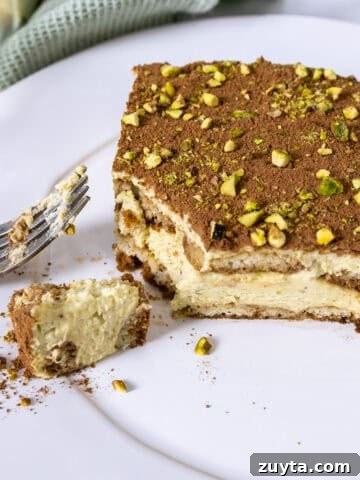 Pistachio Cream tiramisu on a plate with a forkful scooped out.