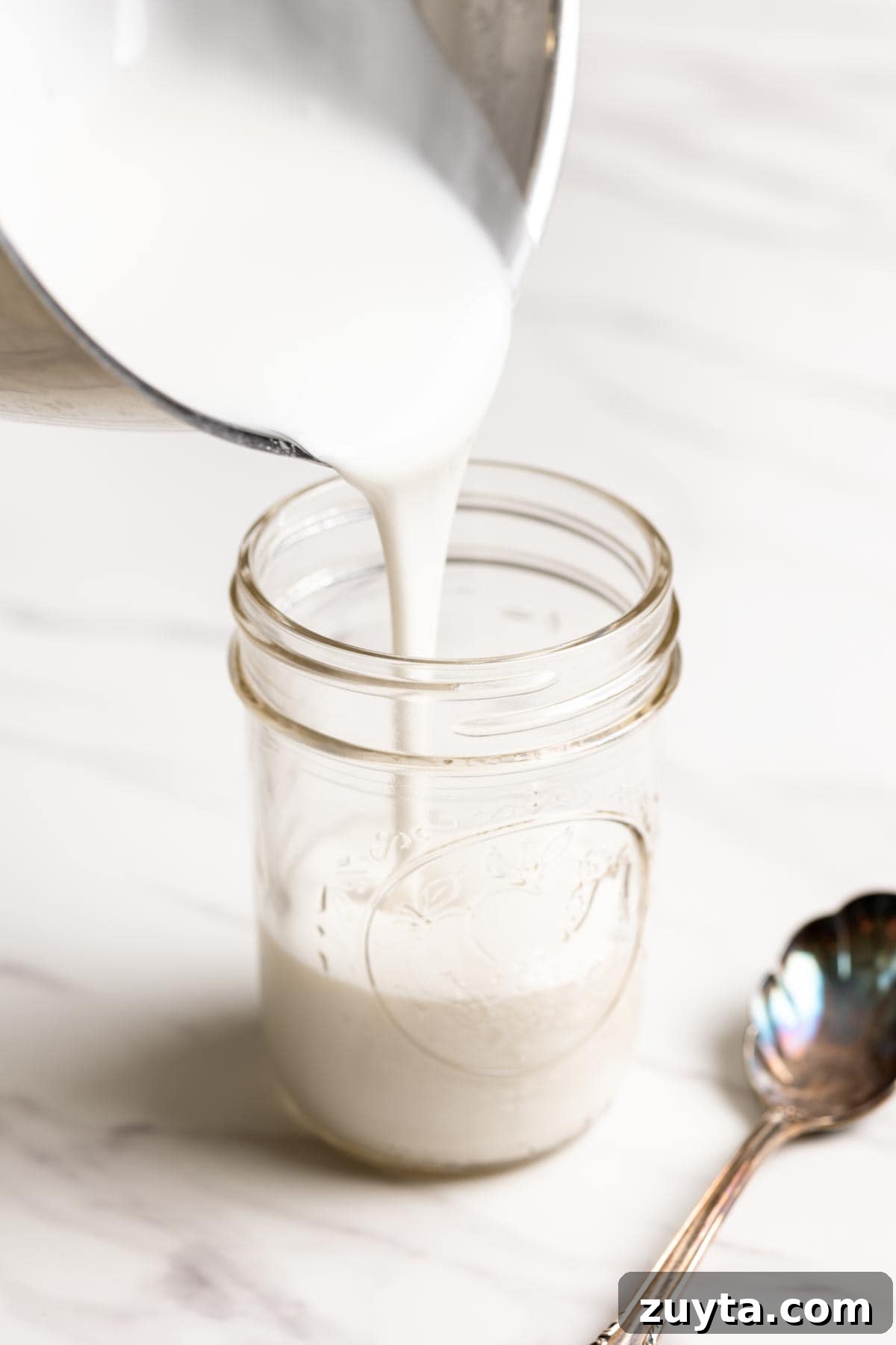 Coconut sauce is being transferred to a glass jar.