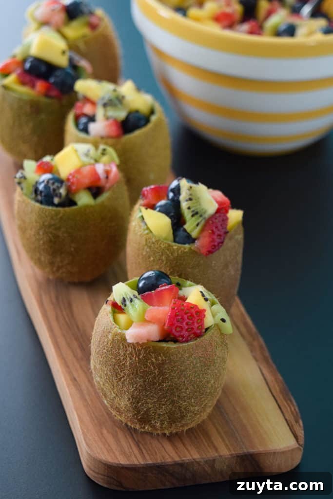 Tropical Fruit Salad in Kiwi Cups Recipe 5 Close up view of tropical fruit salad in kiwi cups on wooden platter