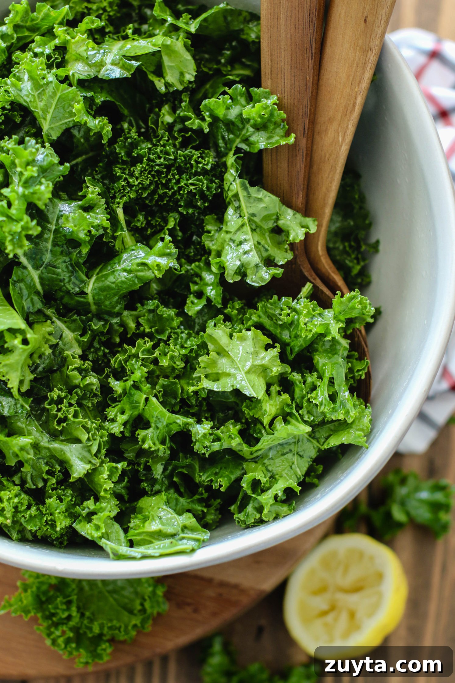 Tempeh and Kale Salad with Cranberries and Apple Recipe 3 kale massaged in bowl with wooden spoons by Flora & Vino
