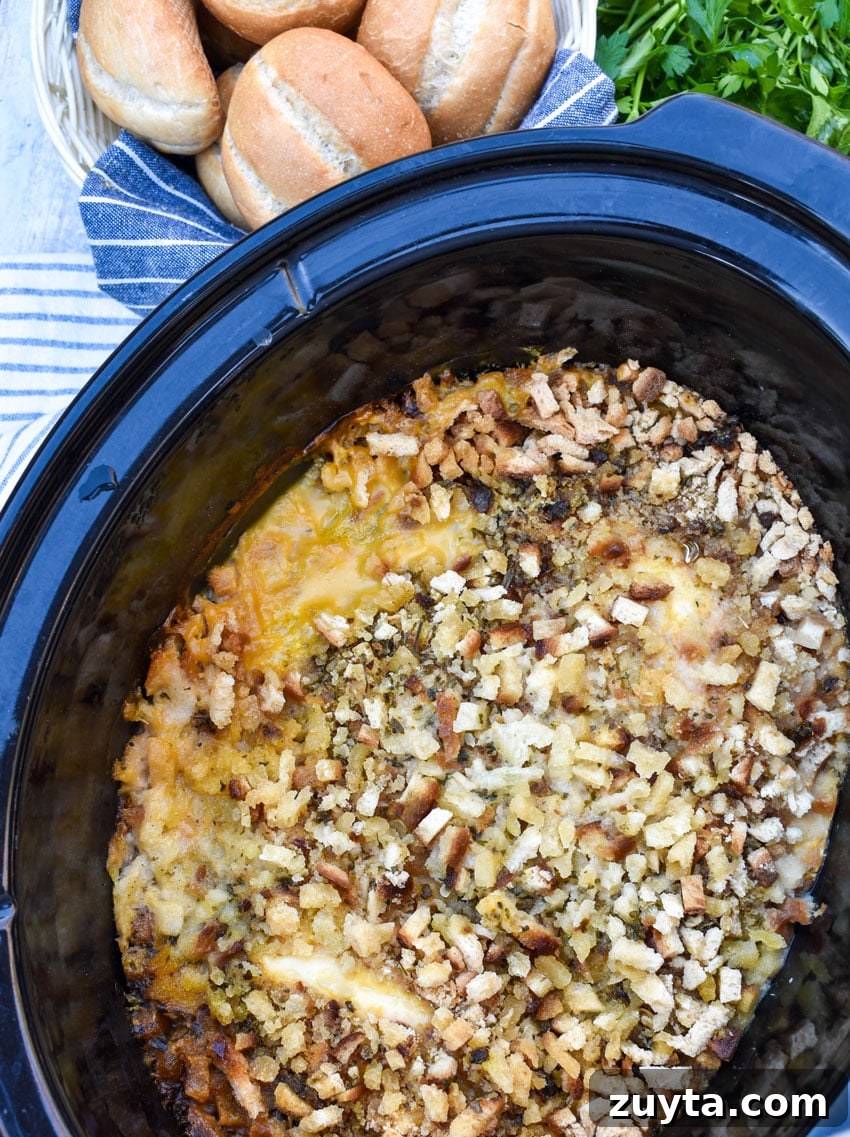 Slow Cooker Chicken Cordon Bleu Recipe with Ham and Swiss 2 stuffing topped layered chicken cordon bleu in the black bowl of a slow cooker