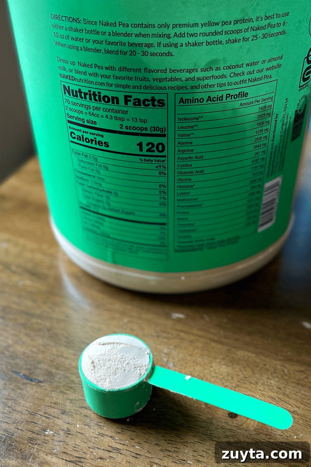 Naked Nutrition Review: Top 3 Protein Powders Compared 6 A scoop of plant-based pea protein powder in focus, with a tub of protein powder in the background.