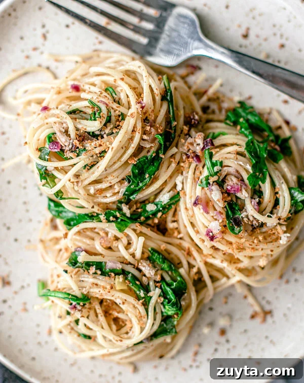 Lemon Pepper Pasta with Sardines twirled onto a plate with bright green arugula.
