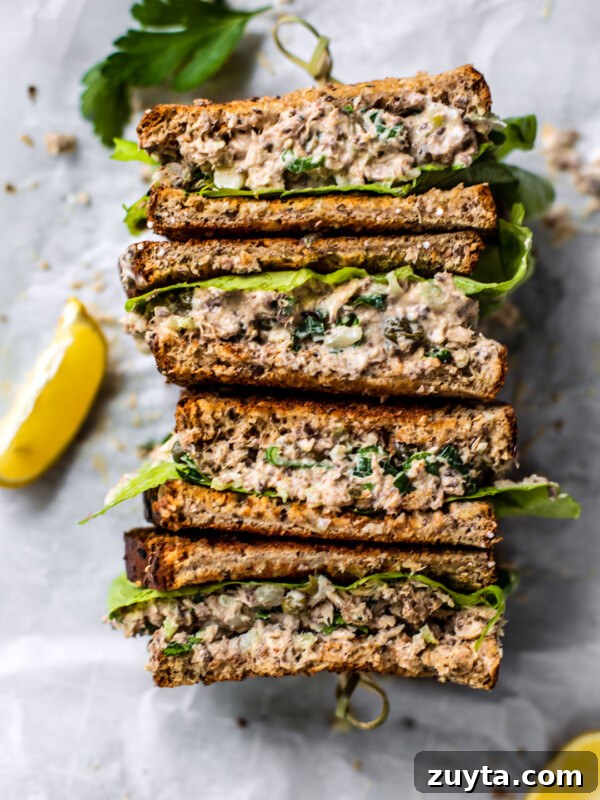 Sardine salad sandwich with lemon wedges.