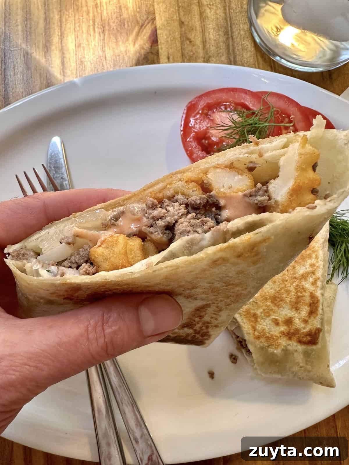 French Tacos Explained: Origins, Ingredients and Where to Try 9 A half of a french taco, held over a plate.