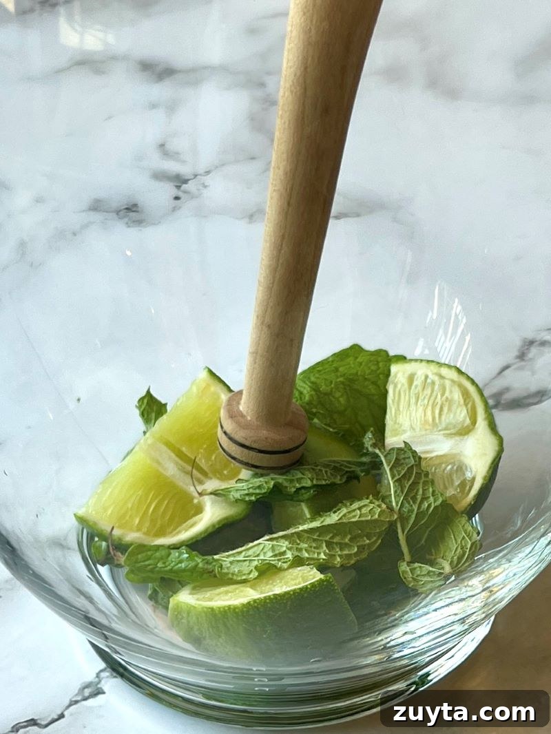 Virgin Mojito Recipe: Mint and Lime Mocktail 3 large glass pitcher with fresh mint and lime wedges with a wooden muddler.