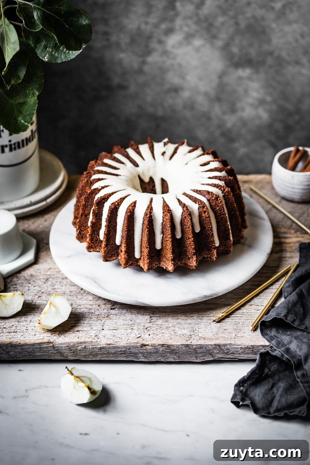 Moist Applesauce Bundt Cake Recipe with Cinnamon Glaze 2 Apple bundt cake with white glaze on a marble platter