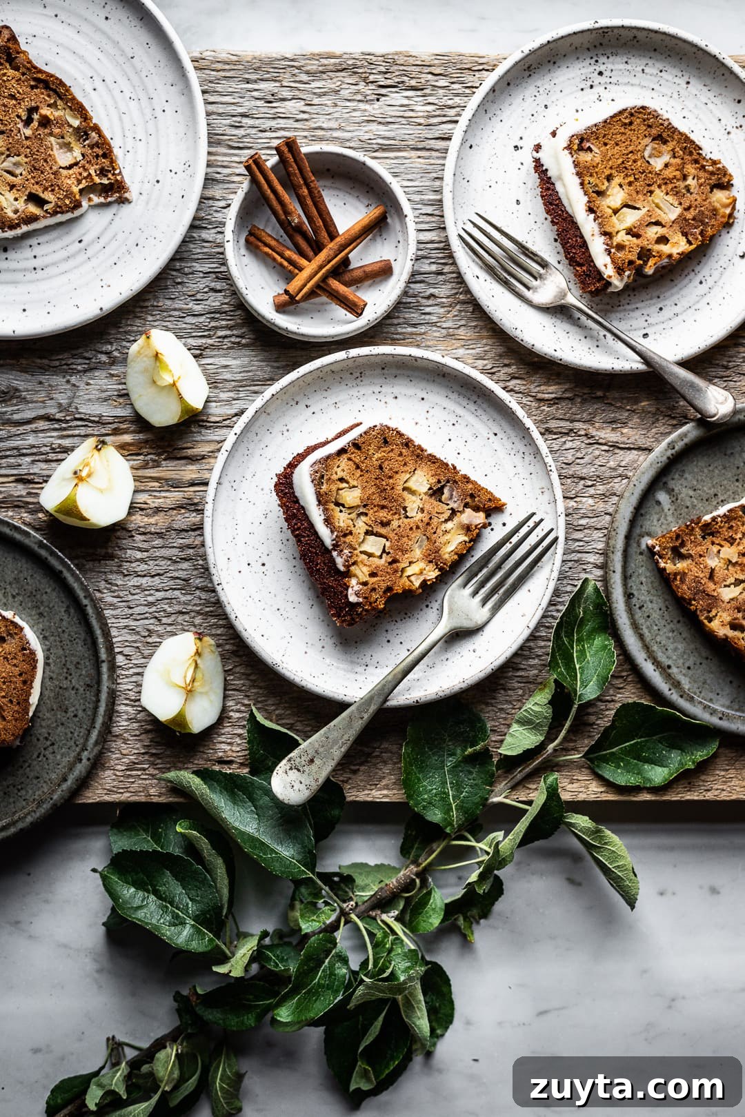 Moist Applesauce Bundt Cake Recipe with Cinnamon Glaze 3 Slices of apple bundt cake on plates with forks, cinnamon sticks and apple slices as decoration