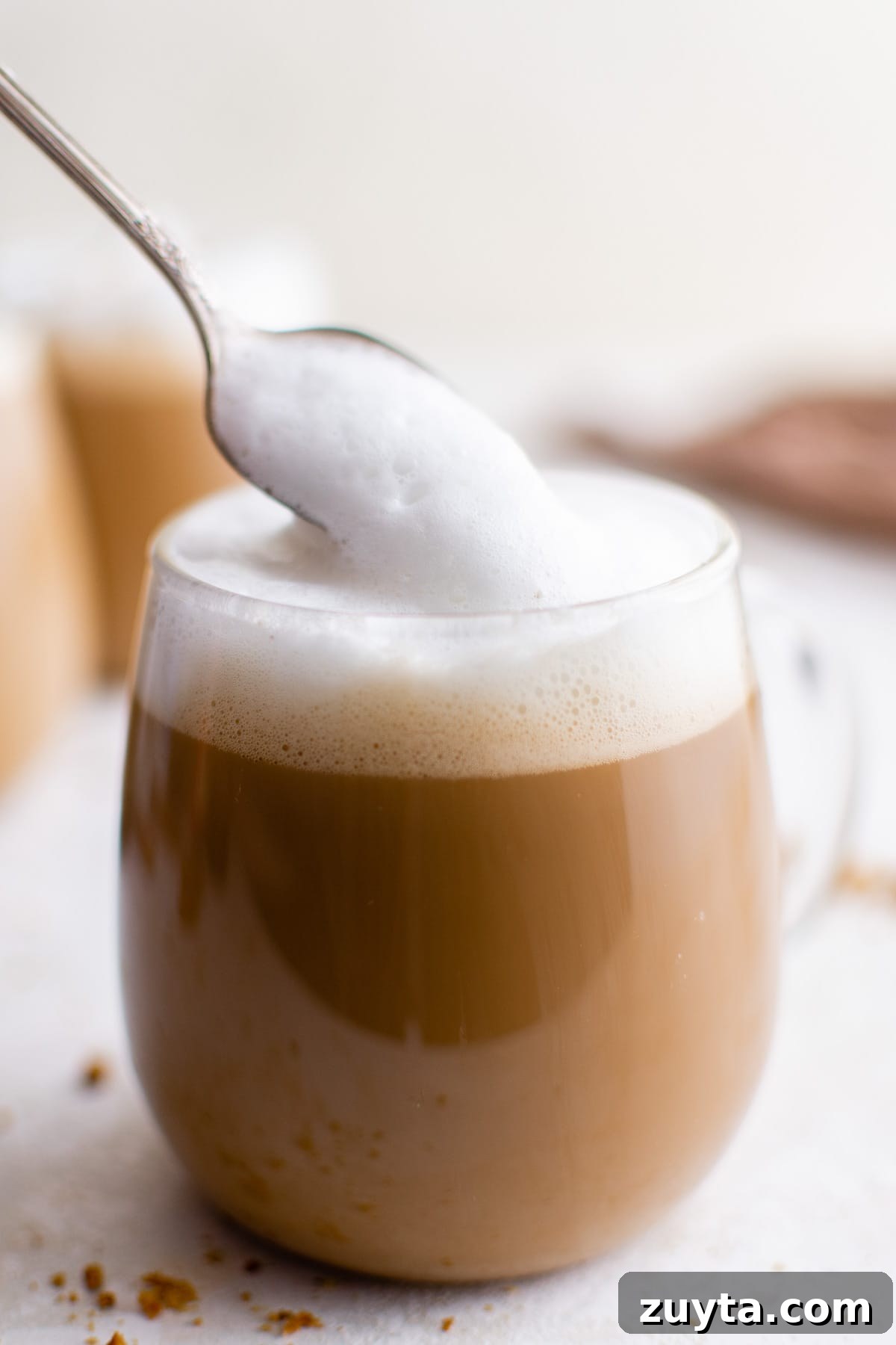 Foamed milk being spooned onto gingerbread latte.