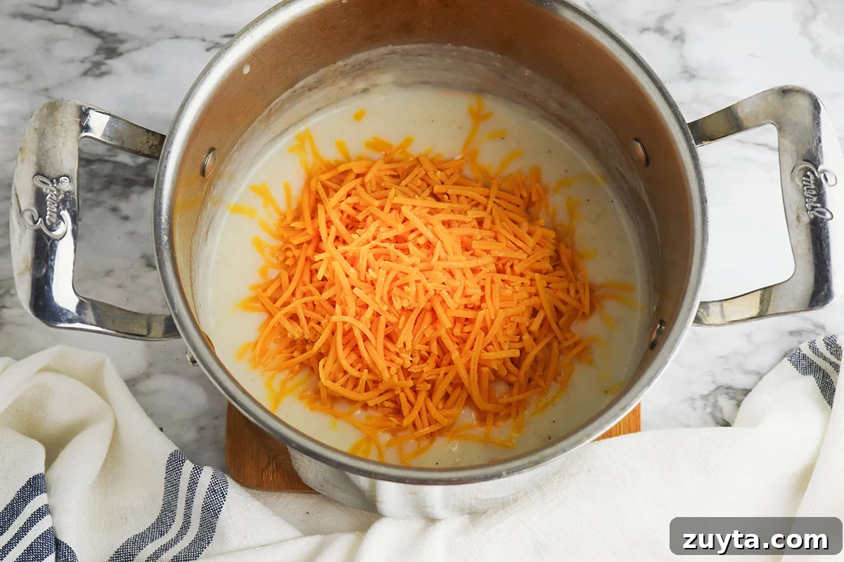 Creamy Cheesy Ham and Potato Casserole 9 Shredded cheese added to ingredients in the saucepan.
