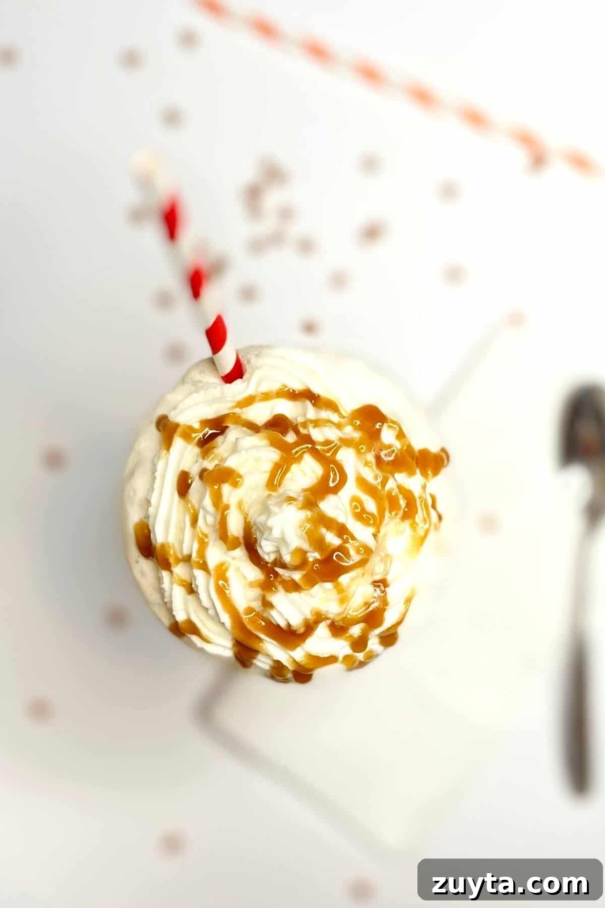 Creamy Butterscotch Milkshake Recipe 5 Top of milkshake, with caramel sauce drizzled on top and a red and white striped straw.