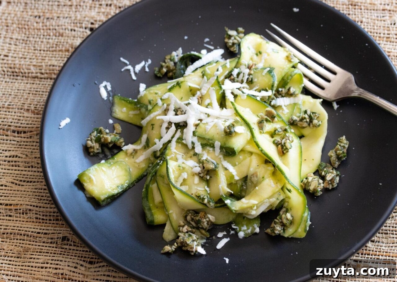 zucchini salad with avocado, pepita parsley gremolata in a black serving plate