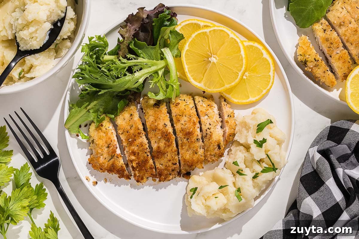 Crispy Italian Chicken Cutlets Recipe 11 A plate with Italian chicken cutlets, salad, mashed potatoes and lemons.