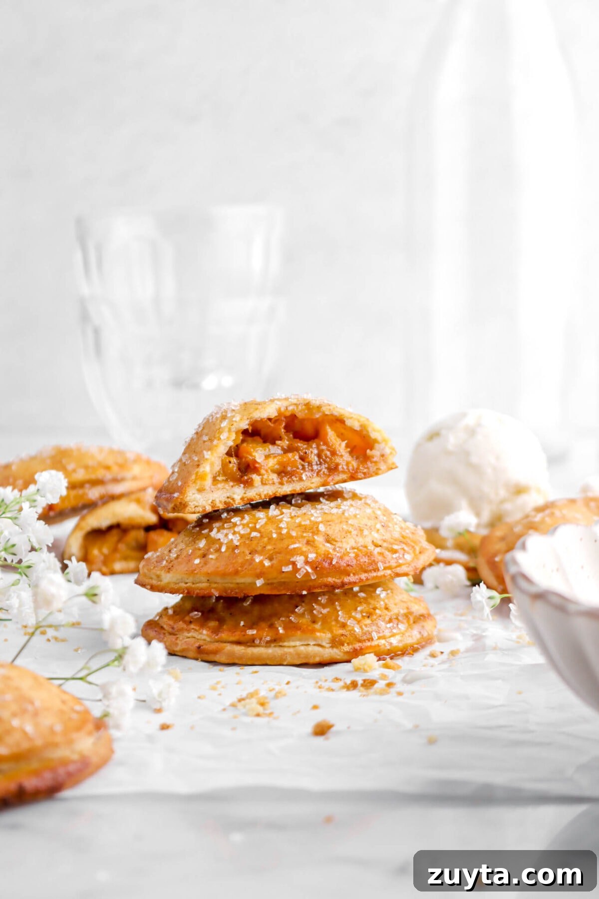 Cinnamon-Spiced Peach Hand Pies Recipe 4 three stacked hand pies with one cut in half on parchment paper