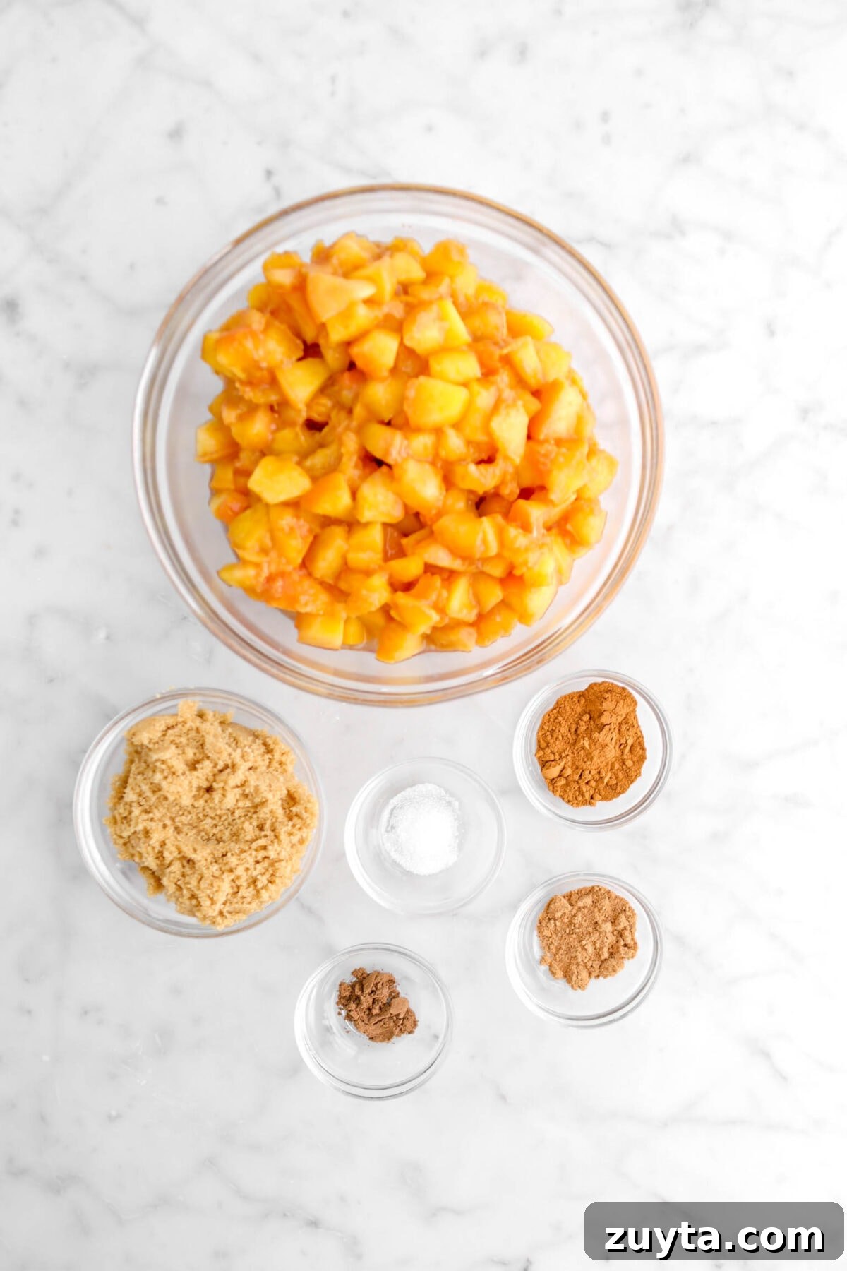 Cinnamon-Spiced Peach Hand Pies Recipe 6 chopped peaches, brown sugar, salt, and spices on marble surface