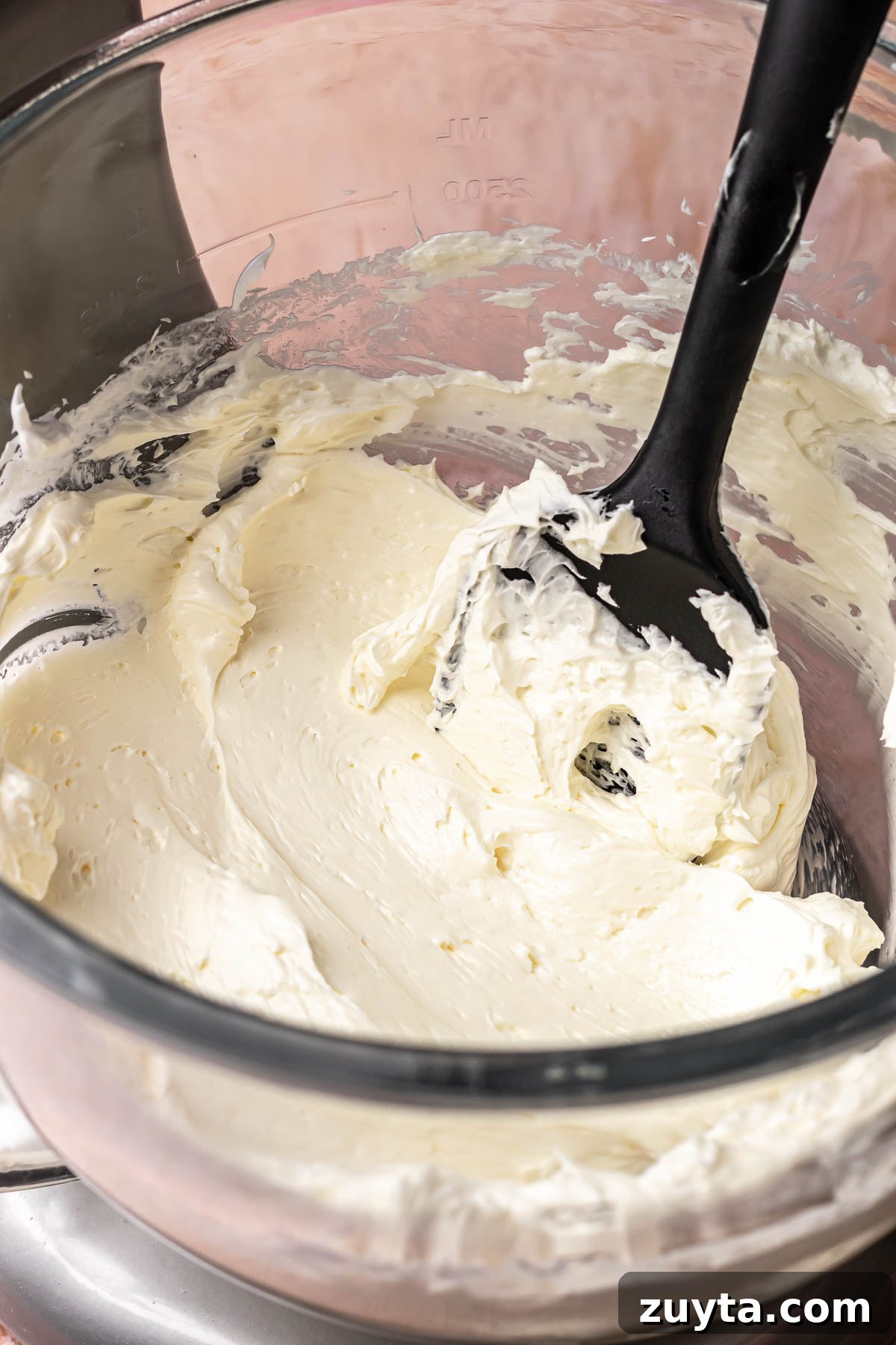Silky Chocolate Swiss Meringue Buttercream Recipe 9 A rubber spatula sits in a bowl of swiss meringue buttercream.