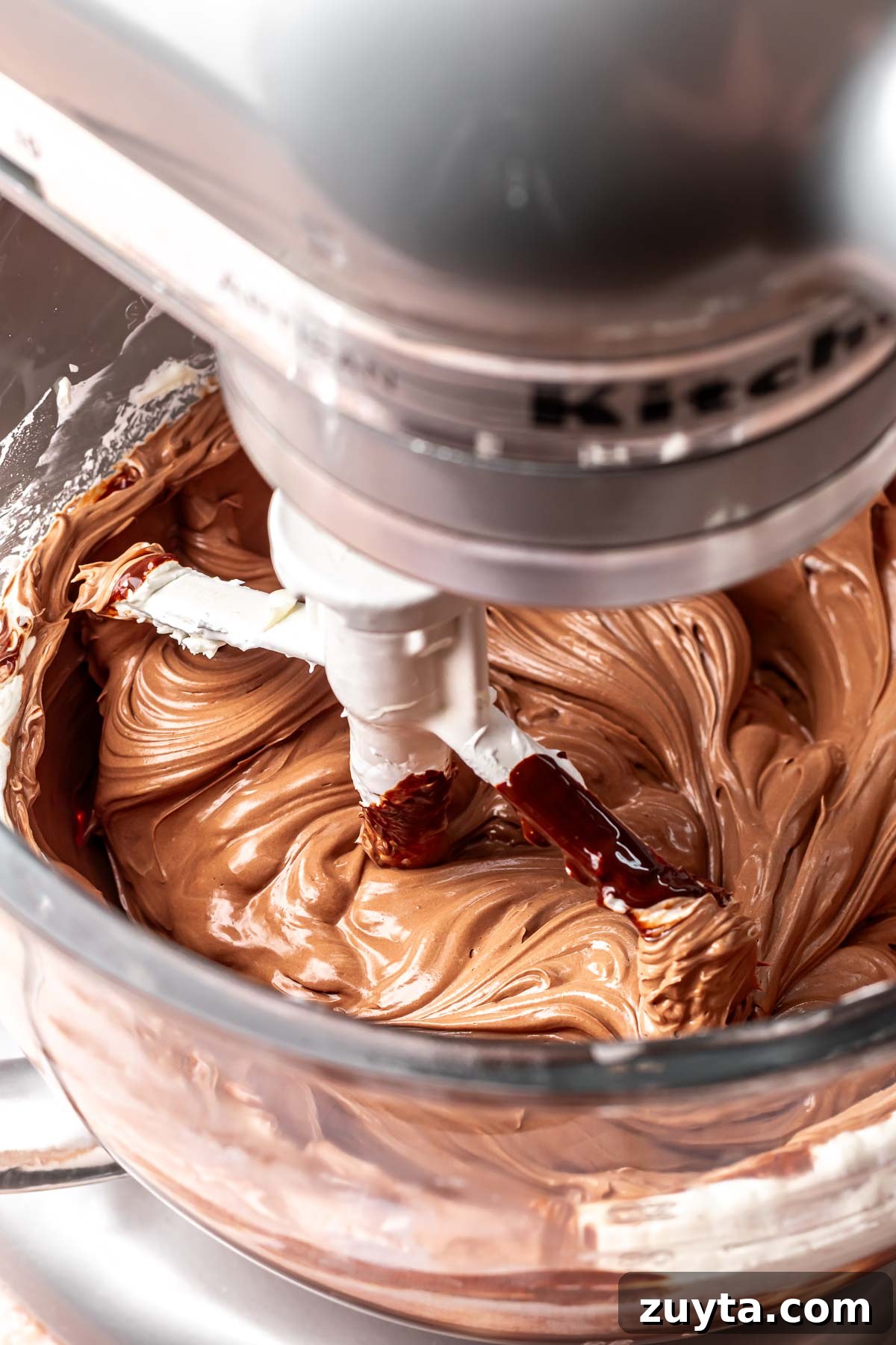 Silky Chocolate Swiss Meringue Buttercream Recipe 10 A stand mixer mixes chocolate into swiss meringue buttercream.