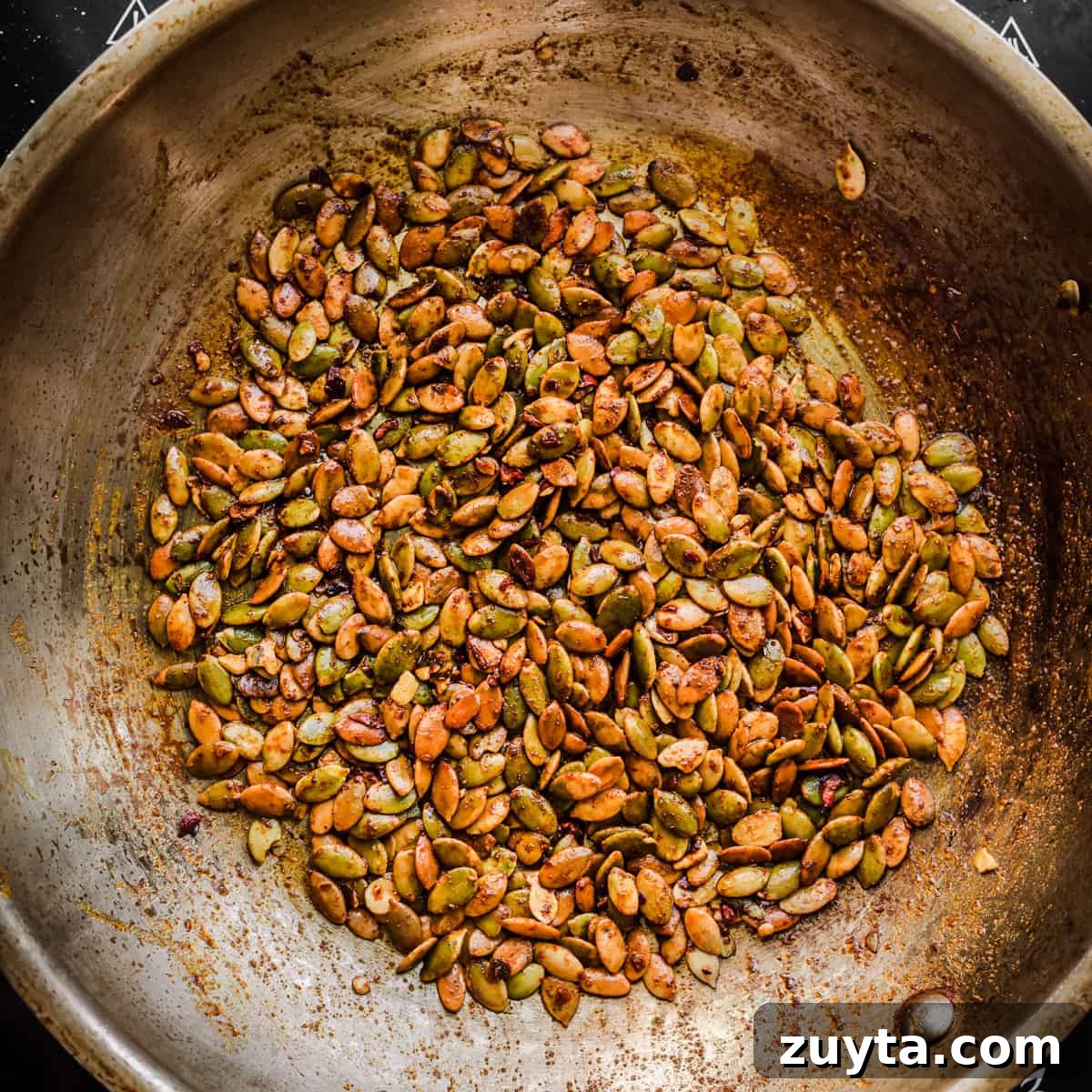 Maple-Roasted Carrots and Dates with Pistachio Pesto 10 Seed sprinkle ingredients in a frying pan after being cooked.