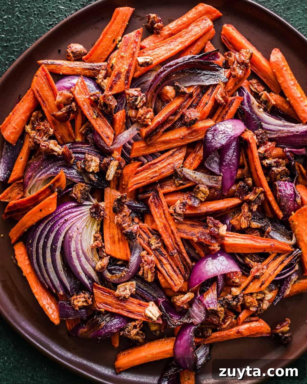 Maple-Roasted Carrots and Dates with Pistachio Pesto 11 Carrots, dates and onions on a brown plate.