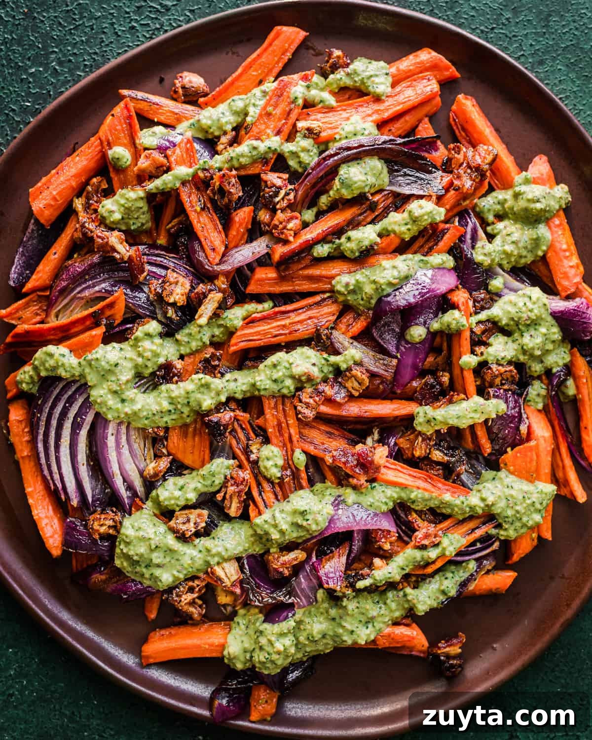 Maple-Roasted Carrots and Dates with Pistachio Pesto 15 Finished carrot and date dish on a brown plate.