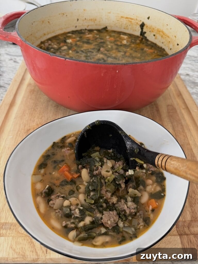One-Pot White Bean and Sausage Soup 14 Using ladle to pour some Sausage and Cannellini Beans Soup from pot into white soup bowl.