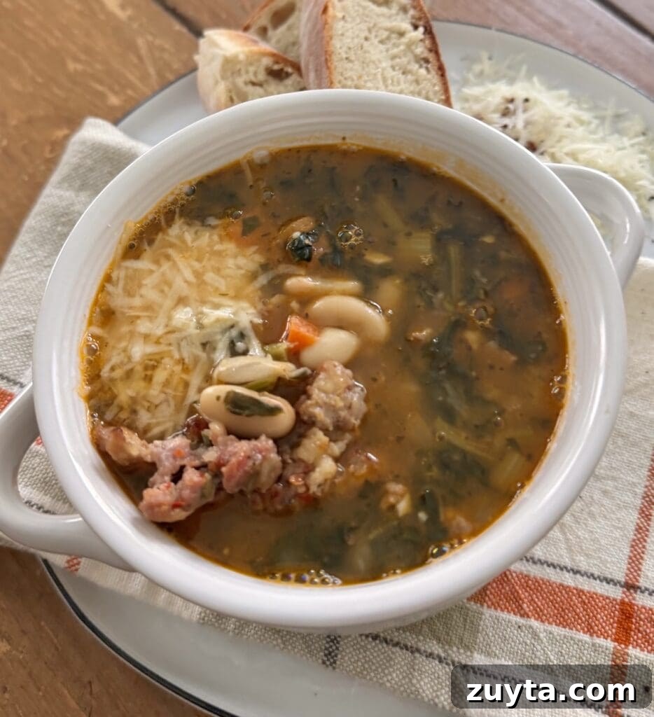 One-Pot White Bean and Sausage Soup 15 Cannellini Bean Soup with Sausage in small white soup bowl with some grated cheese.